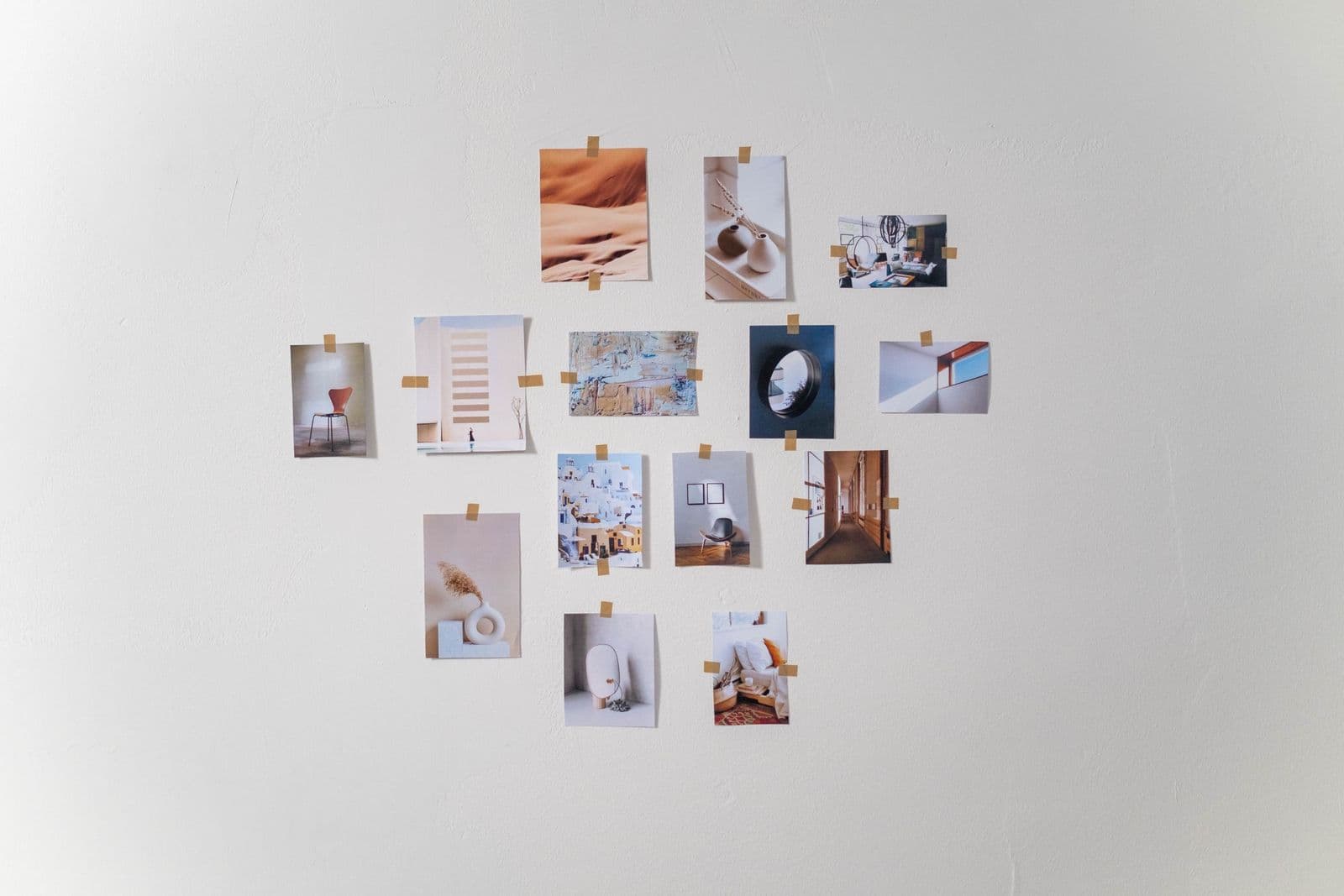 Small photo prints taped to a white wall in a heart-shaped arrangement that is easy to swap and refresh.