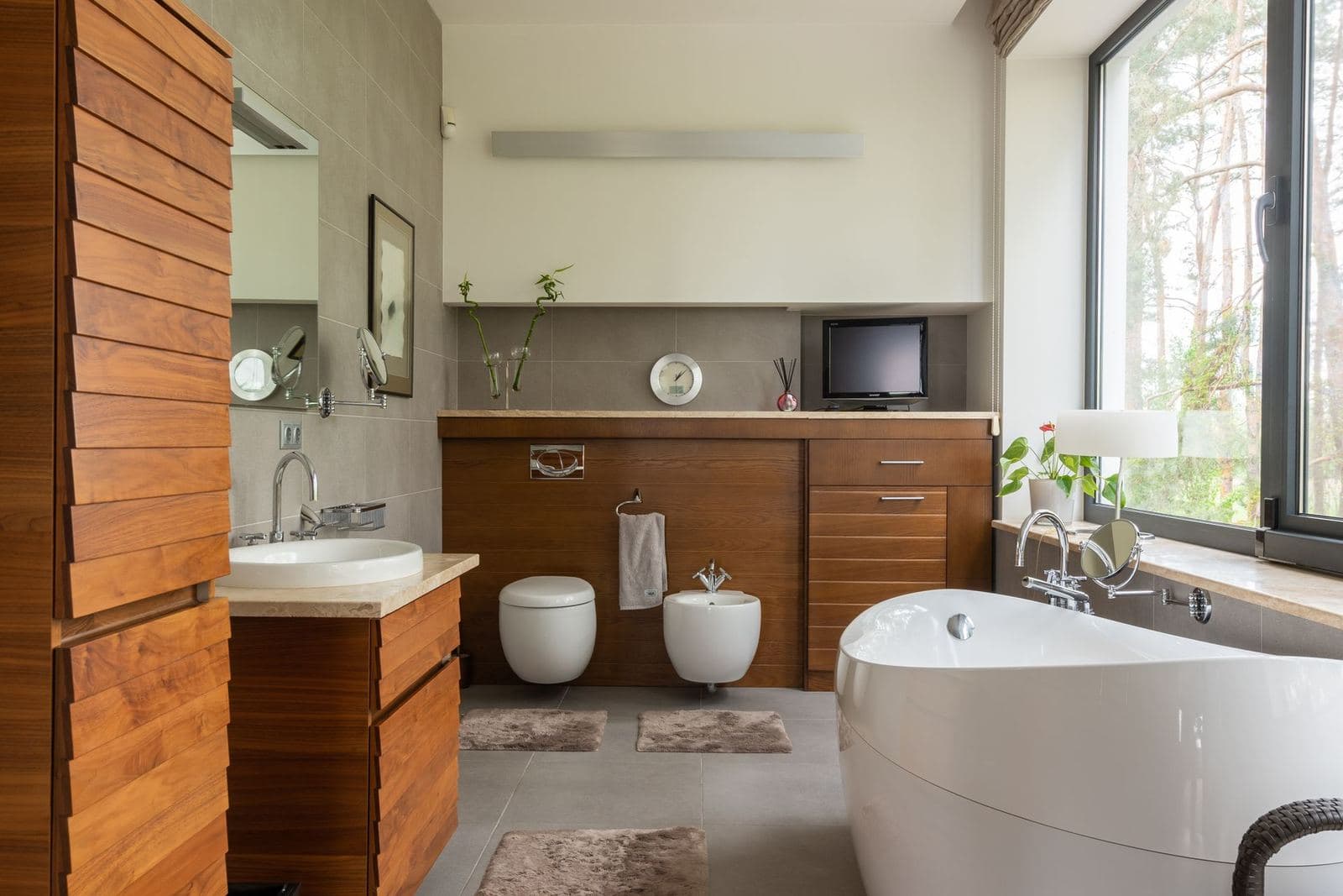 Spacious bathroom with a wood vanity and freestanding white tub, with a small framed print beside the mirror.