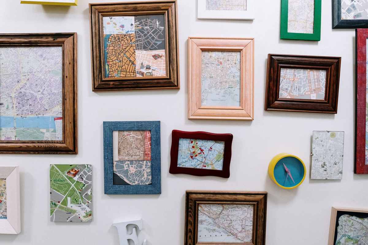 Wall covered with city maps in wooden frames of different sizes and colors