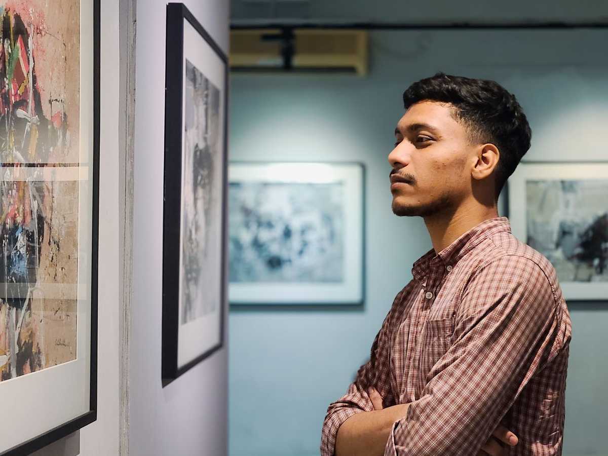 A man looking closely at framed prints hanging on the walls of an art gallery