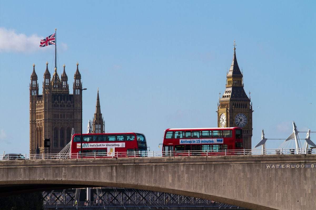 Two red double-decker buses crossing Waterloo Bridge in London with Big Ben and the Houses of Parliament behind them
