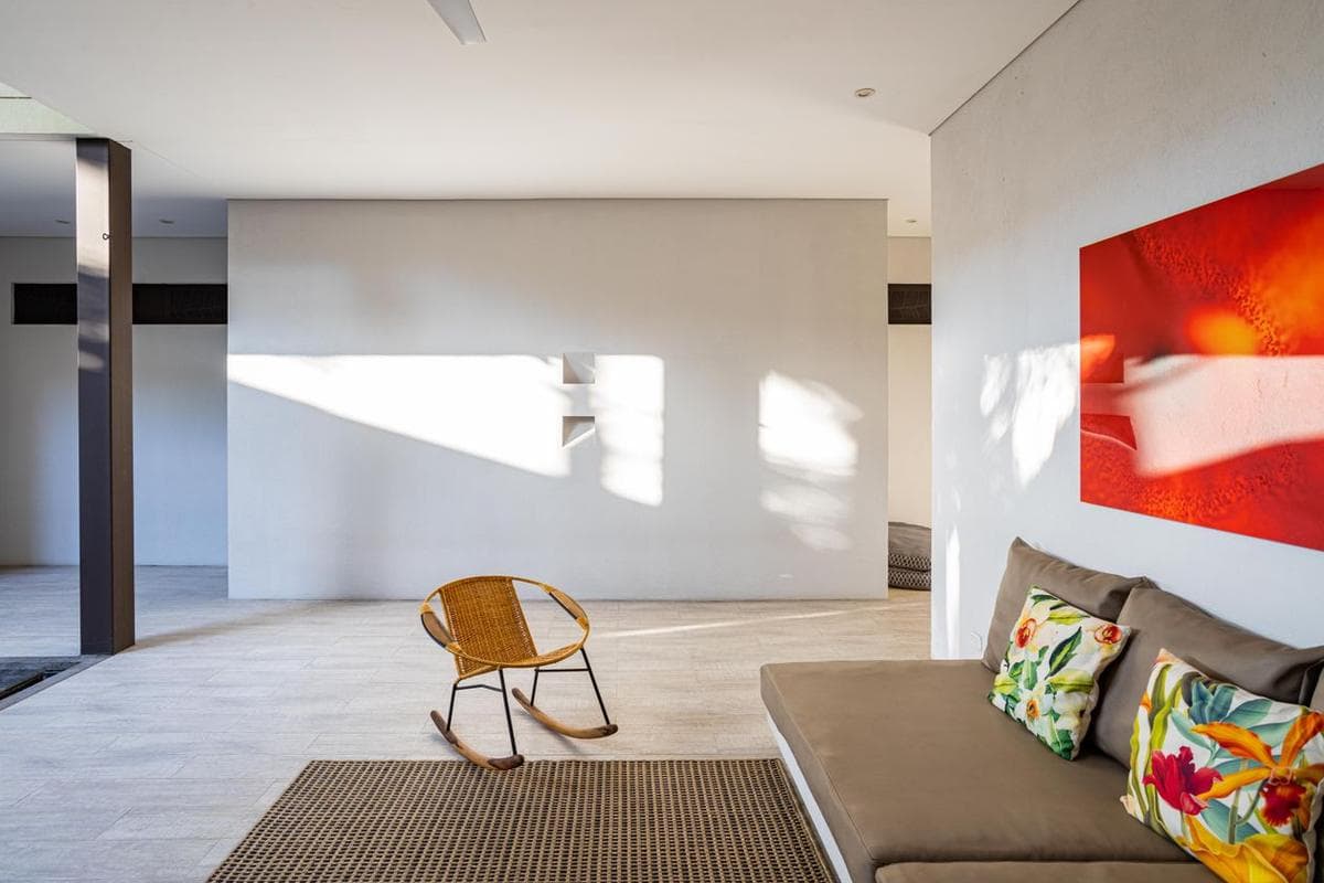 Sunlight streaming across a minimalist living room with a large red painting above a sofa